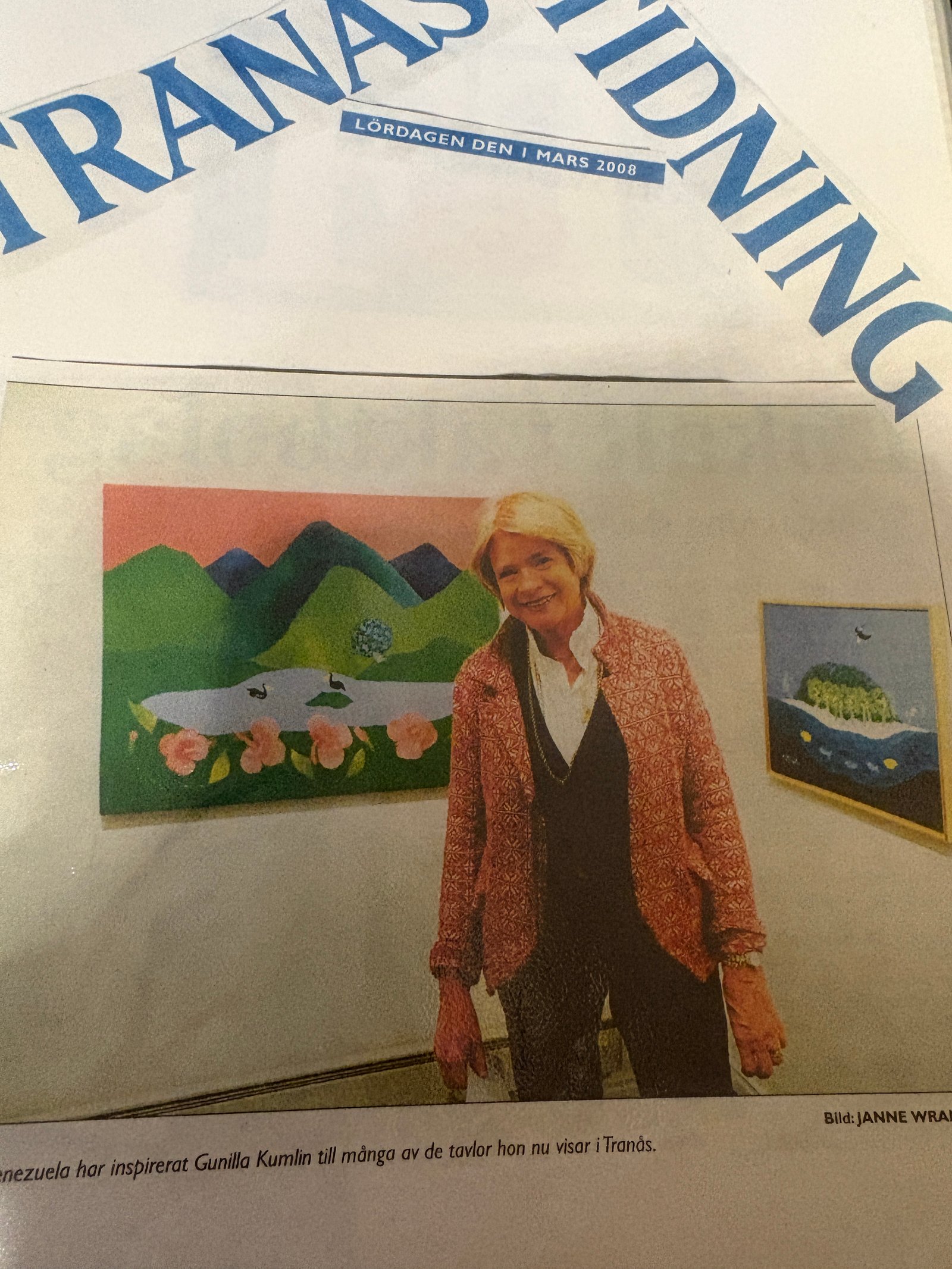 Gunilla framför färgstarka målningar vid en utställning i Tranås